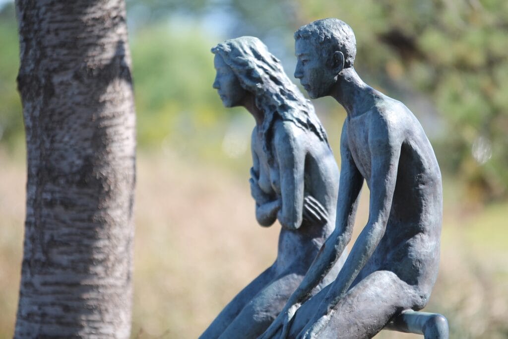 Sculpture représentant un homme et une femme assis l'un à côté de l'autre sans se toucher ni se regarder. Une femme croise les mains en signe de frustration. L'homme est assis tristement. La sculpture illustre un mur entre deux personnes, une barrière dans leur intimité. 