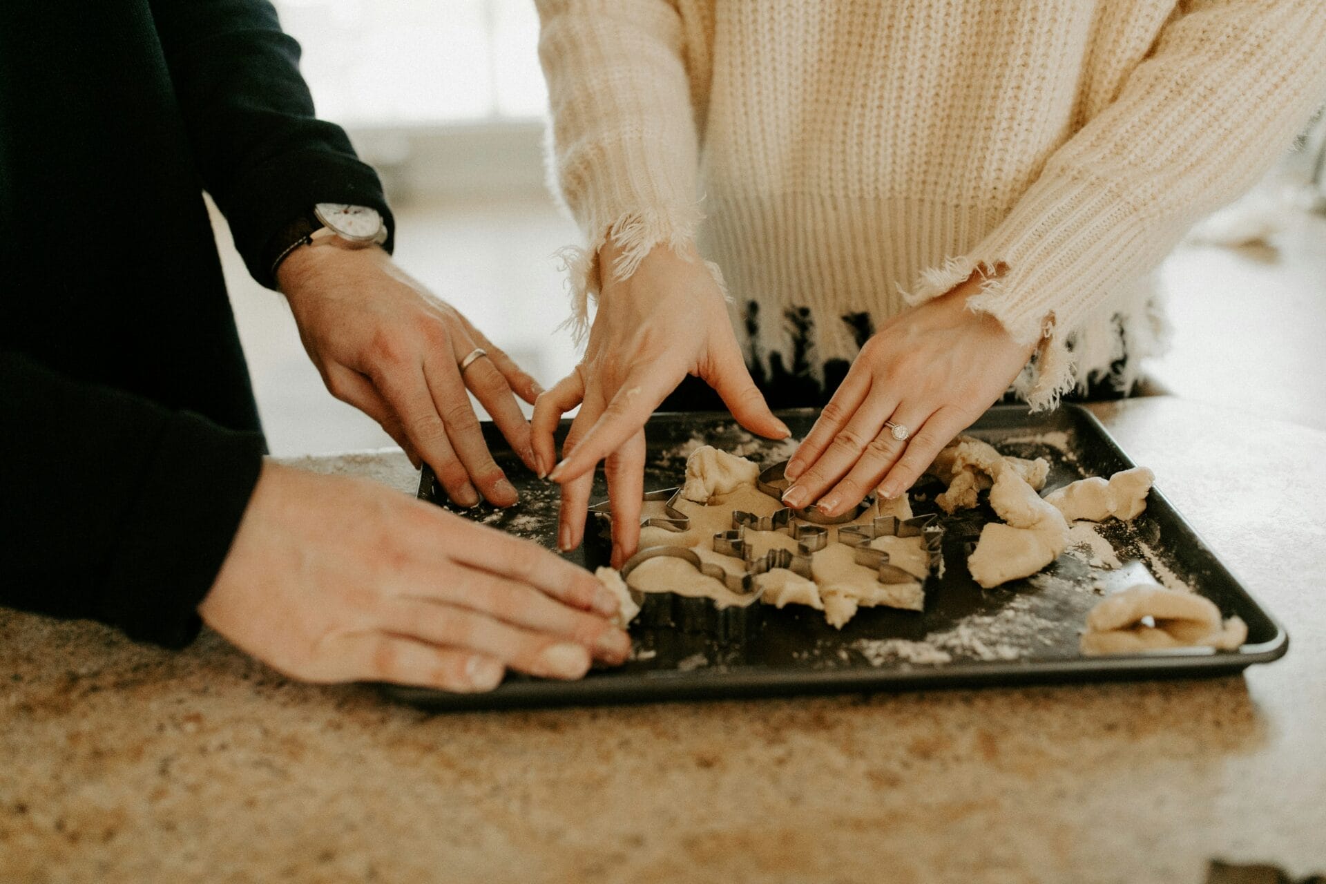 Idée de sortie : cuisiner ou faire de la pâtisserie ensemble. Deux personnes façonnent de la pâte sur une plaque à pâtisserie, s'adonnant à une activité amusante et créative. 